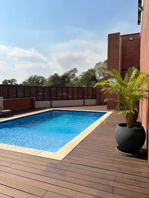 a swimming pool on a wooden deck with a plant at Kruger Living on Nyati in Malelane