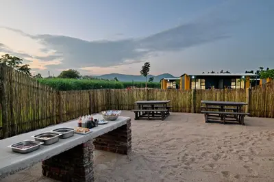a patio with two picnic tables and a fence at SleepOver Malelane in Malelane