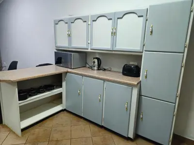 a kitchen with white cabinets and a counter and refrigerator at Light House Lodge in Bela-Bela