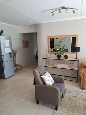a living room with a couch and a chair and a mirror at 258 on Aries in Pretoria