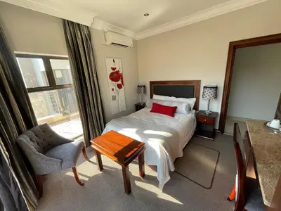 a bedroom with a bed and a table and a chair at Fairview Manor in Modimolle