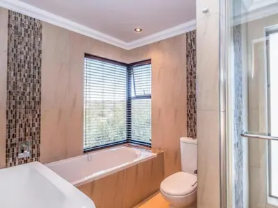 a bathroom with a tub and a toilet and a window at Fairview Manor in Modimolle