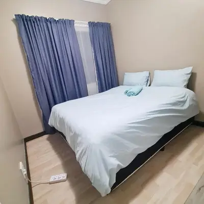 a bedroom with a bed with a blue curtain at Welcome Home in Midrand