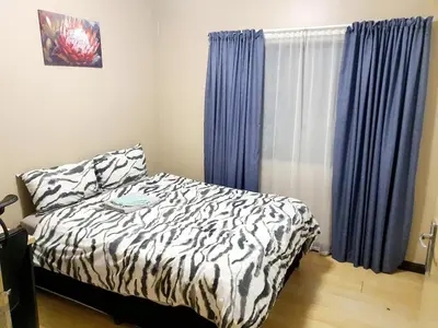 a bedroom with a zebra print bed and blue curtains at Welcome Home in Midrand
