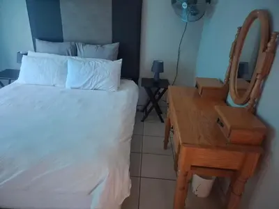 a bedroom with a bed and a table with a mirror at Pendleberry Grove Holidays in Bela-Bela