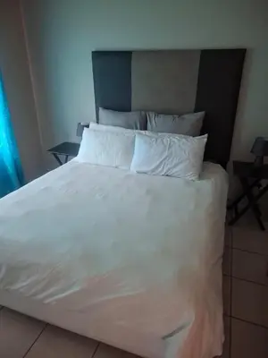 a large bed with white sheets and pillows at Pendleberry Grove Holidays in Bela-Bela