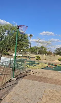 a basketball hoop in a park with a fence at Pendleberry Grove Holidays in Bela-Bela