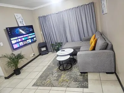 a living room with a couch and a flat screen tv at Oasis Home in Midrand