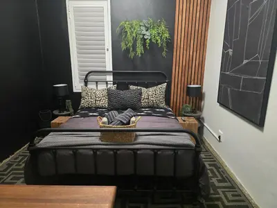 a bed in a room with a black bed frame at The Blue Shutter Guest House in Haenertsburg