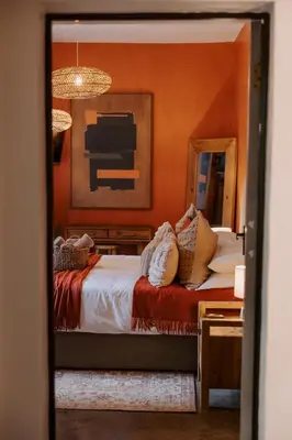 a bedroom with orange walls and a bed and a mirror at The Blue Shutter Guest House in Haenertsburg