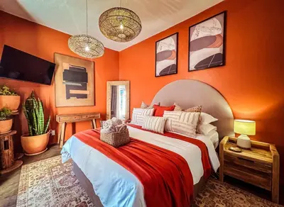 a bedroom with orange walls and a large bed at The Blue Shutter Guest House in Haenertsburg