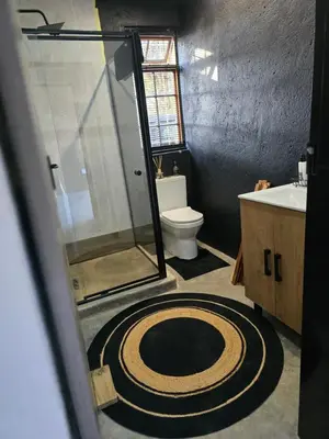 a bathroom with a shower and a toilet and a rug at The Blue Shutter Guest House in Haenertsburg