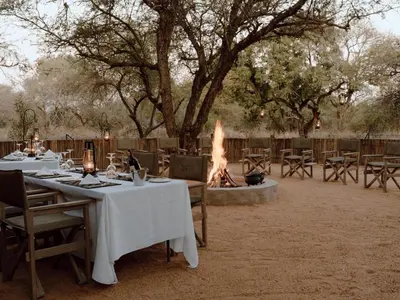 a dining area with tables and a fire pit at Leopard's Bend Bush Lodge in Hoedspruit