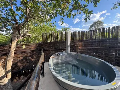 a bath tub sitting next to a fence with a tree at Mbekka Lodge, Mabalingwe in Moheme