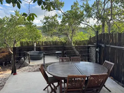 a patio with a table and chairs and a bath tub at Mbekka Lodge, Mabalingwe in Moheme