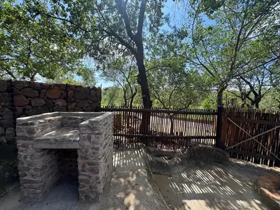 a stone fireplace in front of a fence at Mbekka Lodge, Mabalingwe in Moheme