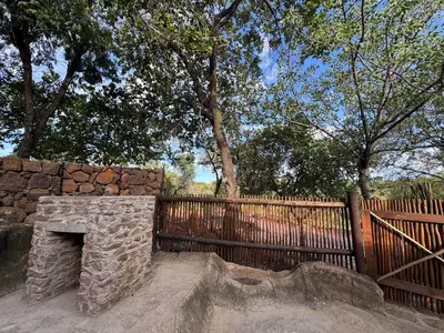 a stone fireplace in front of a fence at Mbekka Lodge, Mabalingwe in Moheme