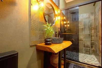 a bathroom with a shower with a table and a mirror at Wild Whispers in Marloth Park