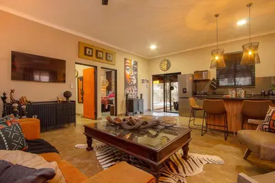 a living room with a table and a kitchen at Wild Whispers in Marloth Park