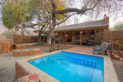a swimming pool in a yard next to a house at Wild Whispers in Marloth Park