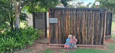 two children sitting in front of a wooden fence at Sand River Cottages in Hazyview