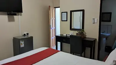 a bedroom with a bed and a desk and a mirror at Sand River Cottages in Hazyview