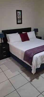 a bedroom with a large bed with white and purple sheets at Sand River Cottages in Hazyview