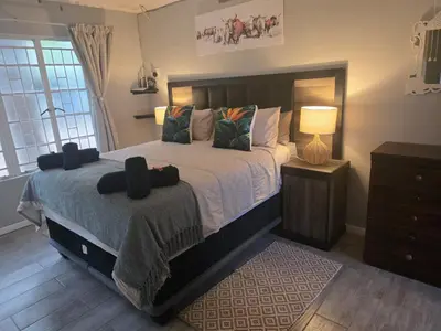 a bedroom with a bed with a lamp and a dresser at Nguni Rest in Barberton