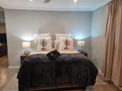 a bedroom with a bed with pillows and two lamps at Nguni Rest in Barberton