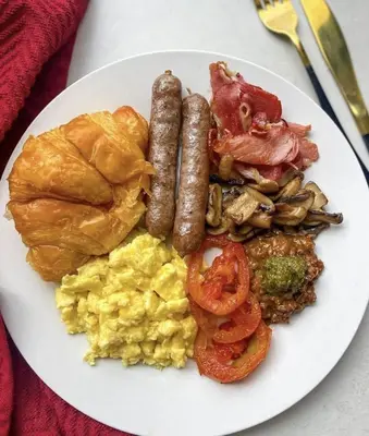 a plate of breakfast food with sausage and eggs at Nteto guesthouse in Dwarsloop