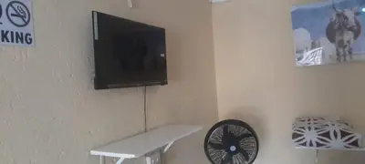 a tv on a wall with a table and a fan at Nteto guesthouse in Dwarsloop