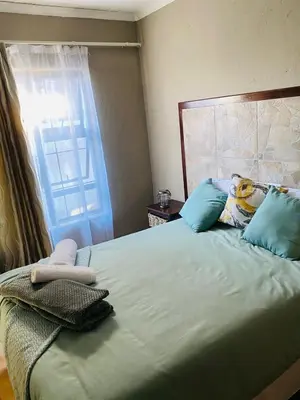 a bedroom with a large bed with blue pillows and a window at Nteto guesthouse in Dwarsloop