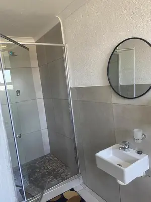 a bathroom with a shower and a sink and a mirror at 606 Guesthouse in Bushbuckridge
