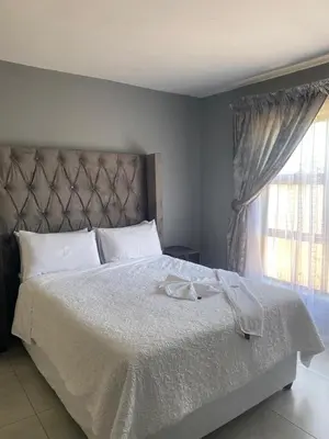 a bedroom with a large white bed with a window at 606 Guesthouse in Bushbuckridge