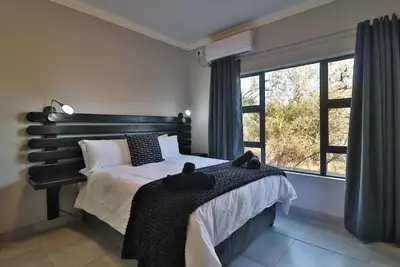 a bedroom with a bed and a large window at Kruger Stories at Marloth in Marloth Park