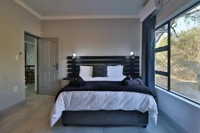 a bedroom with a large bed and a large window at Kruger Stories at Marloth in Marloth Park