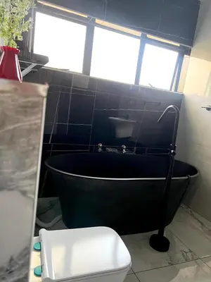 a bathroom with a black bath tub and a toilet at The Concept in Centurion