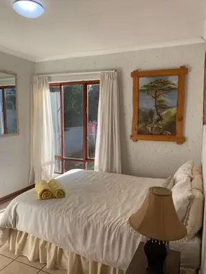 a bedroom with a bed with a lamp and a window at Stay in Woodhill Golf Estate near Pretoria East Hospital in Pretoria
