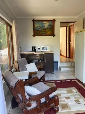 a living room with two chairs and a table at Stay in Woodhill Golf Estate near Pretoria East Hospital in Pretoria