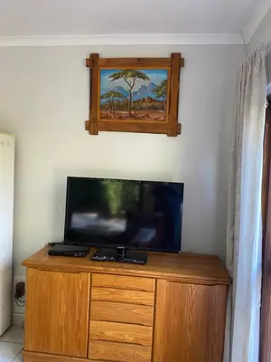 a flat screen tv sitting on top of a wooden dresser at Stay in Woodhill Golf Estate near Pretoria East Hospital in Pretoria