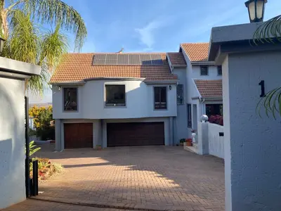 a white house with a garage and a palm tree at Stay in Woodhill Golf Estate near Pretoria East Hospital in Pretoria