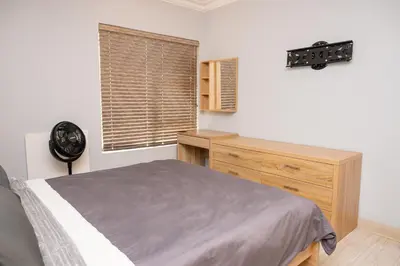 a bedroom with a bed and a dresser and a window at Premium Deluxe at waterkloof in Pretoria