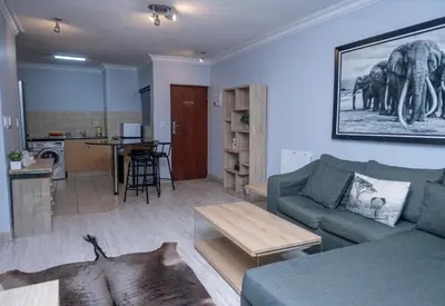 a living room with a blue couch and a table at Premium Deluxe at waterkloof in Pretoria