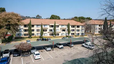 an apartment building with cars parked in a parking lot at Premium Deluxe at waterkloof in Pretoria