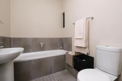 a bathroom with a toilet and a sink and a bath tub at Mkhonto's waterfall ridge in Midrand
