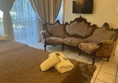 a living room with a bed and a couch at The Elephant Room at Frederick's Place in Pretoria