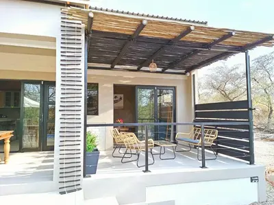 a patio with chairs and a wooden pergola at Longneck Luxury Bush Lodge in Marloth Park