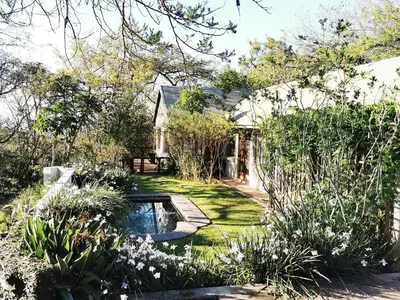 a garden with a pond in the middle of a yard at Hardy-da Forest Cottage in White River