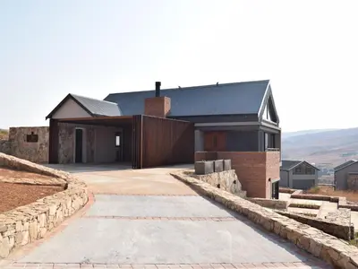 a house with a black roof and a driveway at Hururu House in Dullstroom