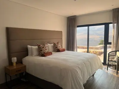 a bedroom with a large bed with a large window at Hururu House in Dullstroom